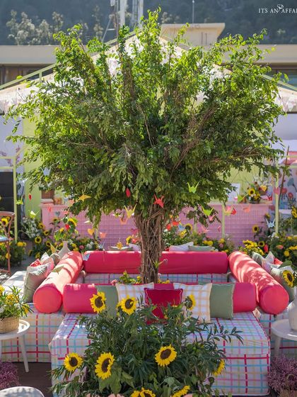A central seating area built around a tree, adorned with colorful paper cranes, creating a whimsical focal point.