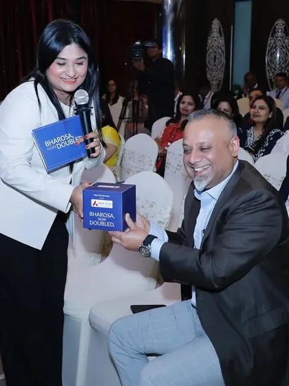 Engaging with a guest during a giveaway segment at the Axis Max Life event.