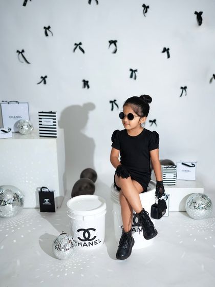 Make way for the diva. This older sister is channeling her inner fashionista with sunglasses and a confident pose in our black and white studio setup.