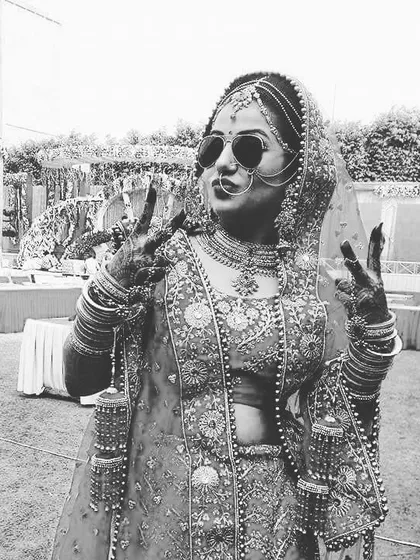 A fun and modern bride showing her cool side with sunglasses and a peace sign, captured in black and white.