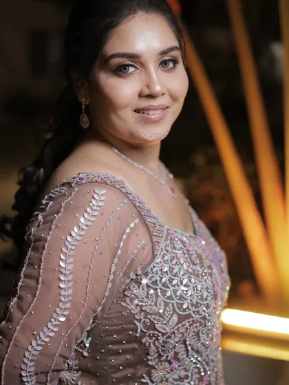 A soft and elegant party look. The makeup enhances her features with subtle contouring and a focus on the eyes, perfect for a sophisticated evening event.