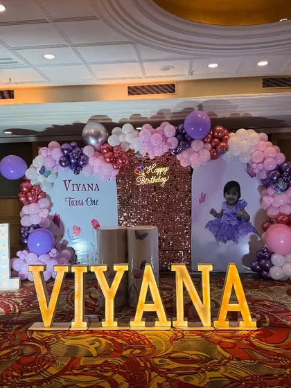 A beautiful butterfly-themed stage for Viyana's first birthday. This setup includes a rose-gold sequin backdrop, a custom-printed panel with her photo, and marquee letters.