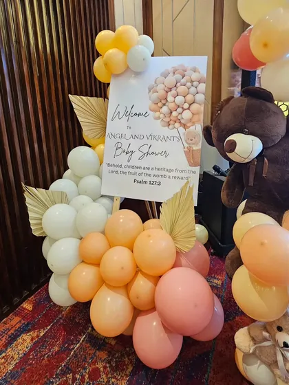 The custom welcome sign for the baby shower, framed by balloons and dried palm leaves, setting a warm and personal tone for the event.