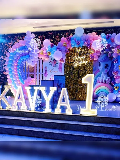 A dramatic, beautifully lit shot of the unicorn and rainbow stage. The lighting enhances the colors and creates a truly magical and immersive atmosphere for the first birthday celebration.