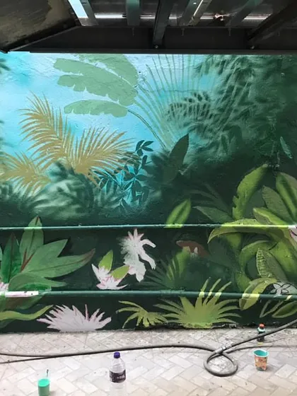 The beginning stages of a forest-themed exterior mural. I used spray paint to create a soft, atmospheric background of jungle leaves.