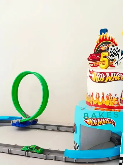 A two-tier Hot Wheels cake that incorporates a real toy track. This interactive design combines a delicious cake with a fun playset for the birthday boy.