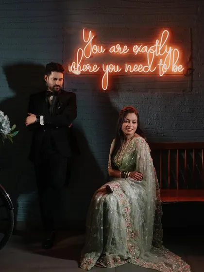 A stylish portrait of a couple posing near a neon sign. This shot combines a modern aesthetic with a classic pose, showing versatility in indoor settings.