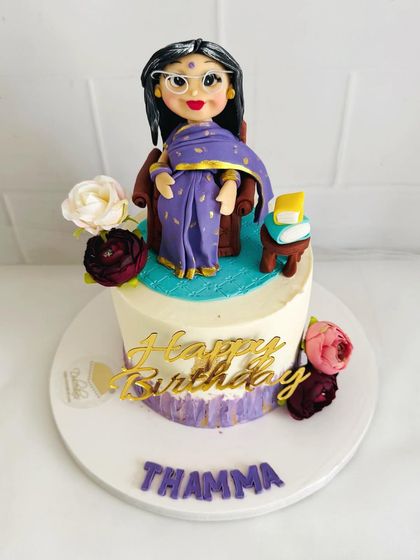An elegant cake for "Thamma" (grandmother), featuring a beautiful fondant figure in a purple saree.