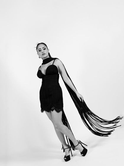 This dynamic pose captures the movement of the fringe scarf, adding a sense of energy and grace to the black and white composition.