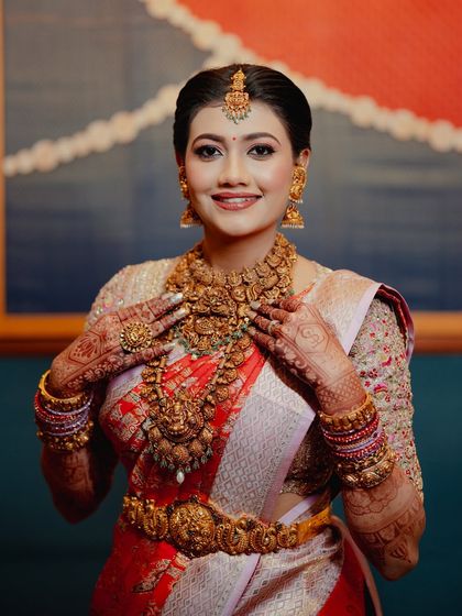 A happy bride showing off her stunning temple jewelry and the beautiful mehendi that completes her bridal look.