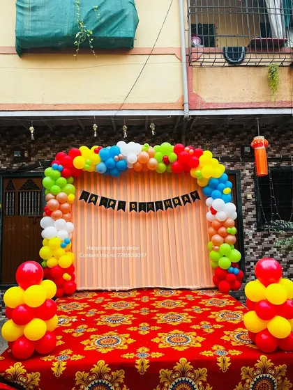 A simple and colorful balloon arch against a plain backdrop, perfect for a small stage or home party.