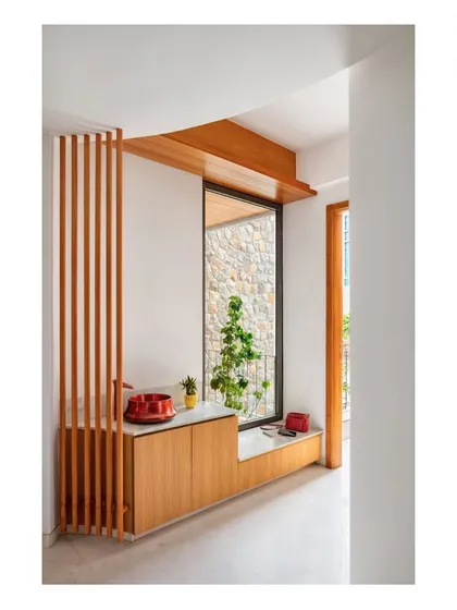 This entryway demonstrates how functional elements can be seamlessly integrated into the architecture. The built-in wooden cabinetry and seating flow into a large window, framing the view of the stone courtyard and blurring the line between inside and out.