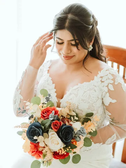 A portrait of the bride holding her colorful bouquet, her soft glam makeup looking flawless.