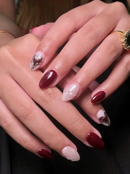 This elegant set combines glossy maroon nails with sheer nails that have sculpted details and a touch of chrome art. It's a perfect mix of classic and modern.
