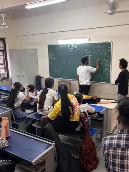Students and fellows collaborate at the blackboard during a music theory lesson. We make learning the fundamentals of music an interactive and engaging group activity.