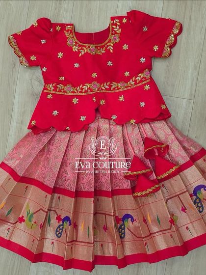 A flat-lay view of this gorgeous red and pink Paithani-style lehenga. You can see the peacock motifs on the border and the delicate latkans.
