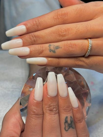 A final look at the elegant milky white extensions, held against a crystal to showcase their clean color and shine.