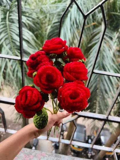 Holding a bunch of my handmade red roses. Each one is crafted with care to create a full and vibrant bouquet that looks beautiful from every angle.