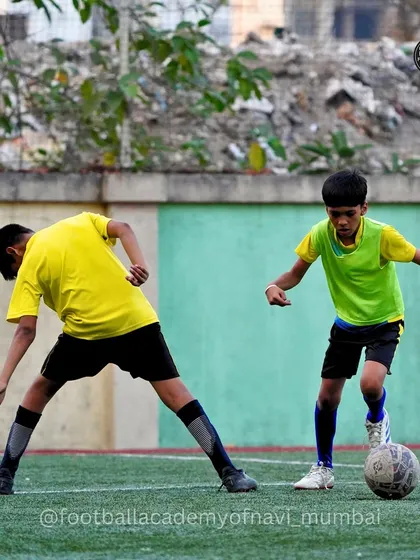 A player in a green bib works on his dribbling skills against a defender.