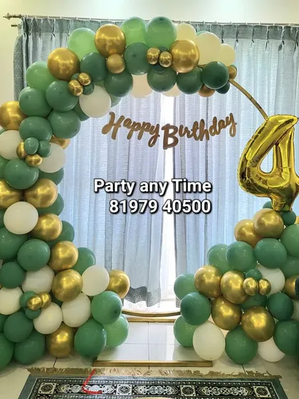 A green and gold balloon arch for a 4th birthday celebration at home.