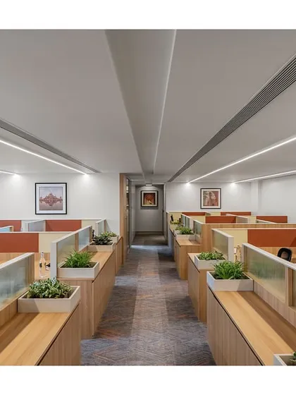 These custom workstations for the IHCL head office, 'The Office with A View', feature an oak laminate base and integrated planters. The design prioritizes a light, airy feel while providing functional elements like writing boards and softboards, enhancing the open-plan office environment.