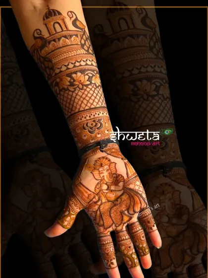A single hand adorned with a beautiful portrait of Lord Ganesha playing the flute. The surrounding arm design features traditional temple and floral patterns.