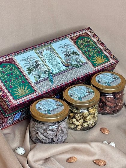 This rectangular designer box features a serene peacock and floral motif. It comes with three jars of premium nuts and dry fruits, making it a compact yet elegant gift choice for the festive season.
