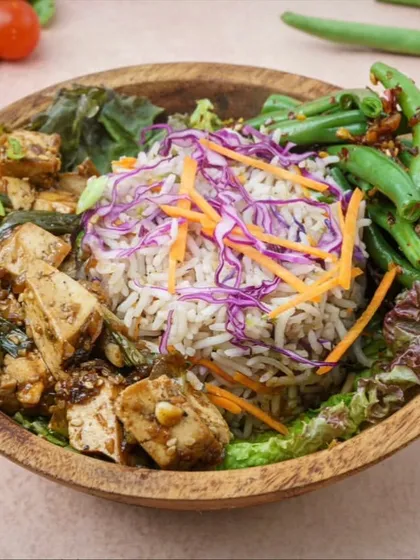 Our Asian Tofu Bowl is a perfect example of a balanced and flavorful meal. It combines protein from the savory tofu, complex carbs from the rice, and plenty of vitamins from the crisp chili garlic green beans and shredded vegetables.
