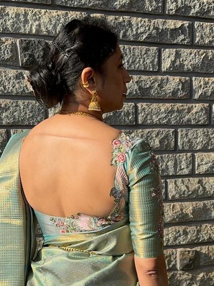 Our signature hummingbird embroidery on a pale blue Kanjeevaram saree blouse, showcasing a unique and artistic design on the back.
