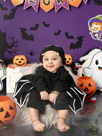 A full view of our Halloween studio setup, featuring a happy baby in a bat costume surrounded by ghosts, pumpkins, and a bubbling cauldron.