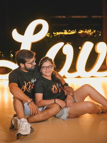 A relaxed and happy couple posing with the illuminated 'Love' sign.