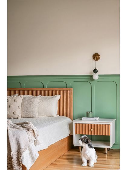 A playful yet chic bedroom designed for a young girl. We created a custom fluted wood headboard and a matching bedside table, set against a bold green paneled wall. The cute dog is not part of the design, but certainly adds to the charm!