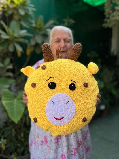 A cheerful giraffe-face cushion, complete with little horns and a happy smile. This piece is sure to be a favorite with kids.