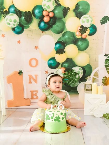 A lovely green-themed first birthday setup, complete with a beautiful cake. This photo captures the moment just before the fun of the cake smash begins.