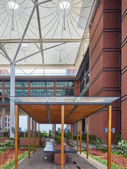 A shaded outdoor seating area at the Wipro Hyderabad campus, located under a large tensile canopy. These spaces provide employees with comfortable areas to work, socialize, and connect with nature during their workday.