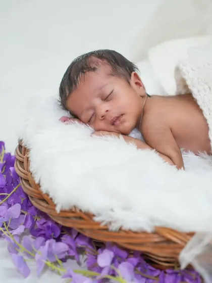 Sleeping peacefully in a wicker basket. This classic pose highlights the baby's smallness and serenity.