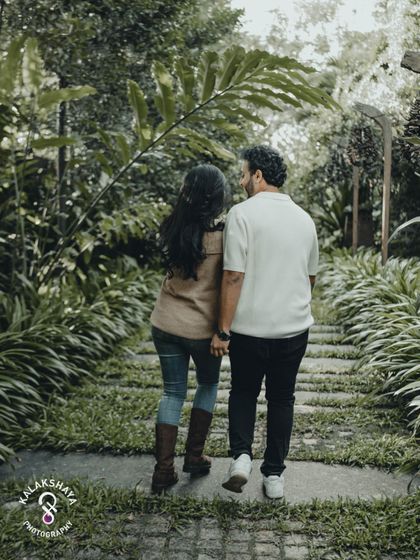 A walk to remember. This shot captures the couple in a natural, candid moment, walking hand-in-hand through a lush green pathway.