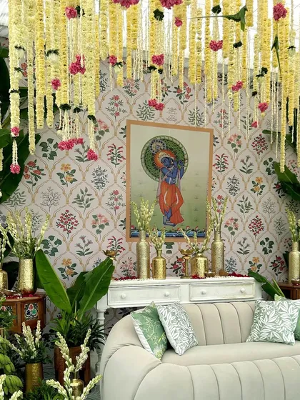 The central seating area for our South Indian themed Haldi, set against a backdrop of Pichwai art and framed by lush greenery and hanging floral strings.