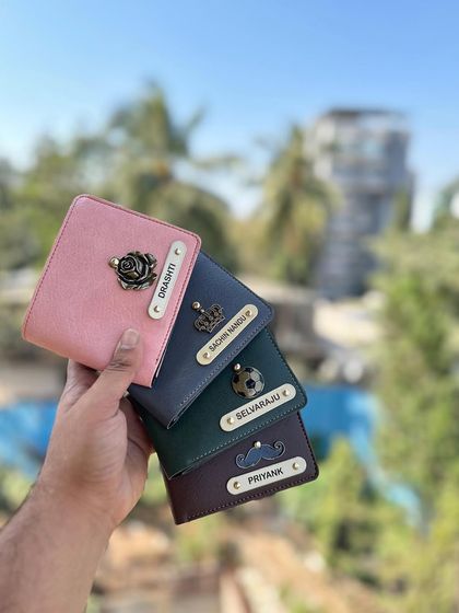 A handful of my personalized NEXON wallets, showing different color and charm combinations like the rose, crown, football, and mustache.