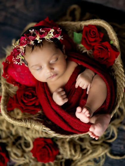 Surrounded by red roses, this sleeping baby is pure beauty. The rich red color is so striking and beautiful for a newborn girl.