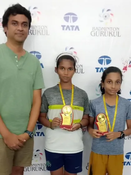 Two young winners with their trophies and a proud parent. We believe in involving the entire family in a player's journey.