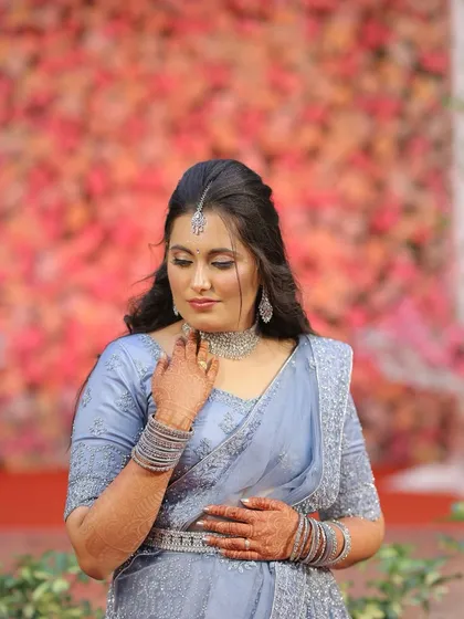 A portrait of elegance for her reception. This look features soft, shimmery eyeshadow, a defined winged liner, and a mauve lip, all coordinated with her beautiful pastel blue lehenga and diamond accessories.
