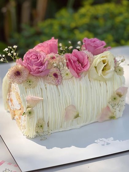 A closer look at the delicate details of my Mango Cream Cheese log cake, showing the textured frosting and the arrangement of fresh flowers and petals.