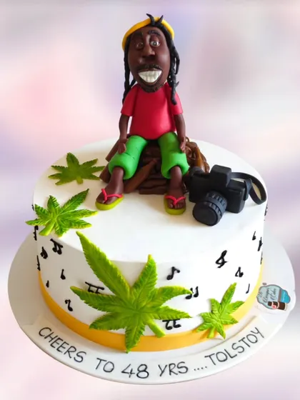 A Rastafarian-themed cake for a 48th birthday. This fun, custom design includes a hand-sculpted figurine, a camera, and musical notes.