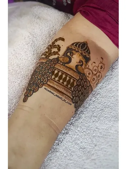 The beginning of a leg design, with two peacocks framing a central architectural element.