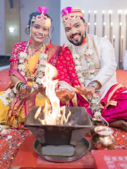 The couple sits before the sacred fire (homa), their happy faces illuminated by the flames. This is a central part of the wedding ceremony, symbolizing their union.