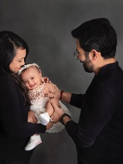 A tender moment between parents and their smiling baby girl. These simple, classic portraits against a dark backdrop are timeless and full of emotion.