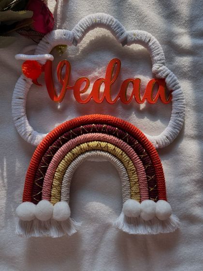 A top-down view of the "Vedaa" name hanging, highlighting the craftsmanship of the rainbow and the custom nameplate.