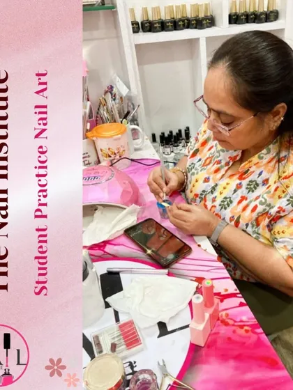 A student practices her nail art skills on a color wheel, surrounded by the tools of the trade.