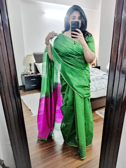 A mirror selfie showing the full drape of the green and pink Chanderi saree. This versatile piece can be dressed up or down for any formal event.